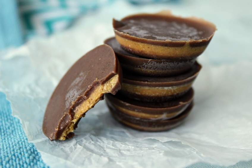 Stack of keto peanut butter cups with one missing a bite and leaning up against the others