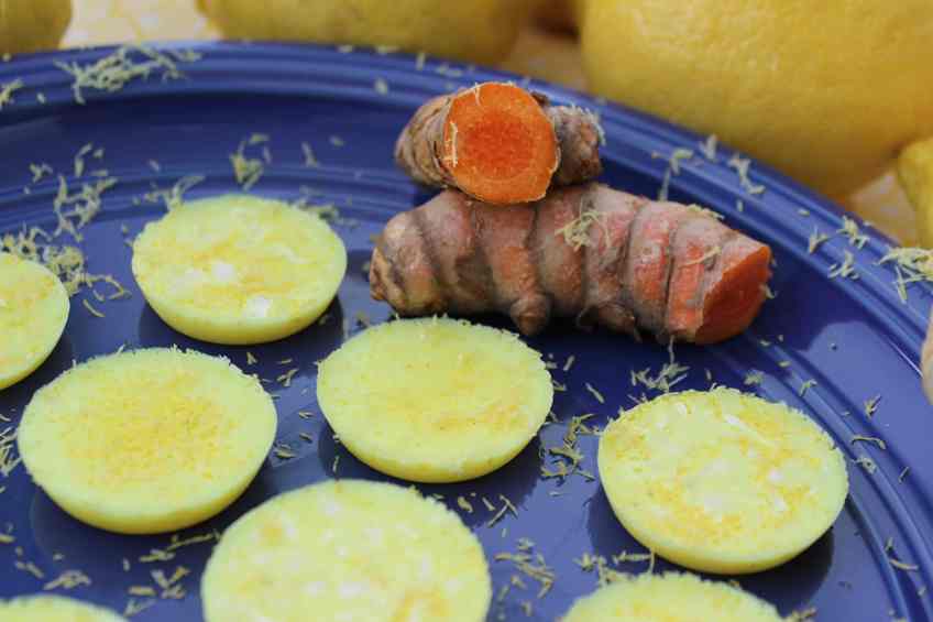 Lemonade fat bombs on a blue plate with turmeric root on the side