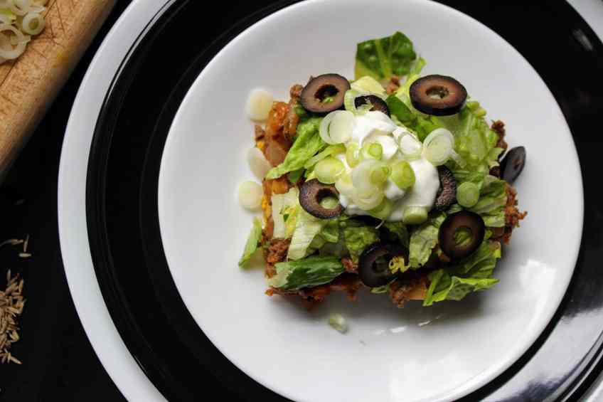 Closeup overhead shot of a serving of Keto Mexican Bubble Pizza on stack of 3 white-black-white plates.