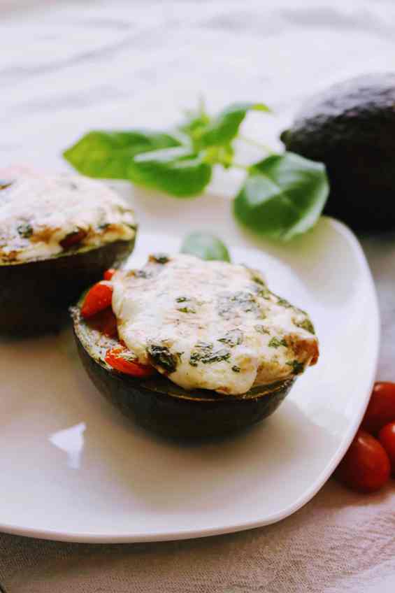 Easy Caprese Stuffed Avocados - Profile shot of stuffed avocados on white plate