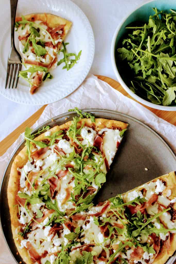 Keto friendly pizza with the best low carb pizza crust and topped with balsamic pizza sauce and prosciutto, goat cheese, and arugula!